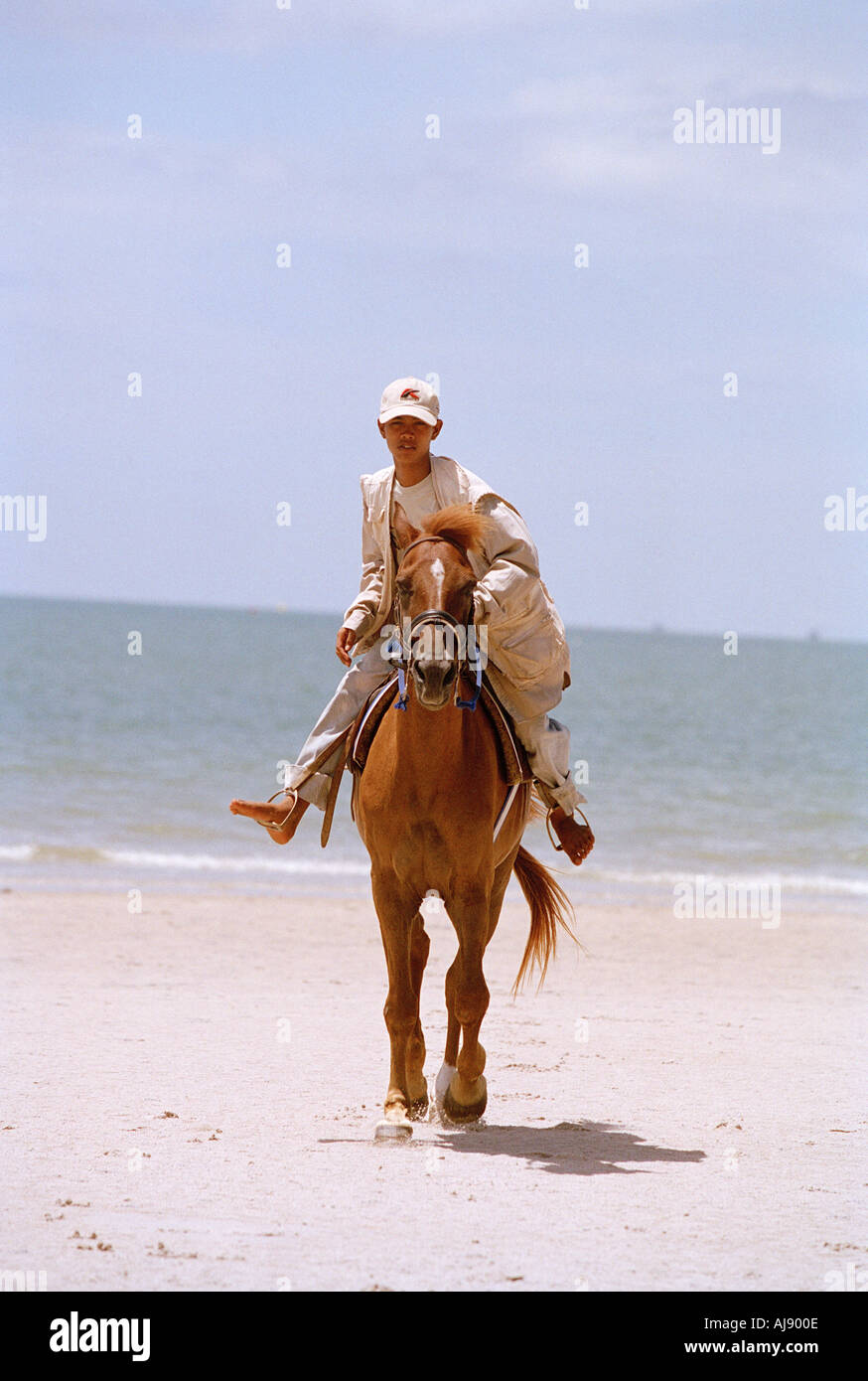 Young boy riding a horse on a Thai Beach Stock Photo
