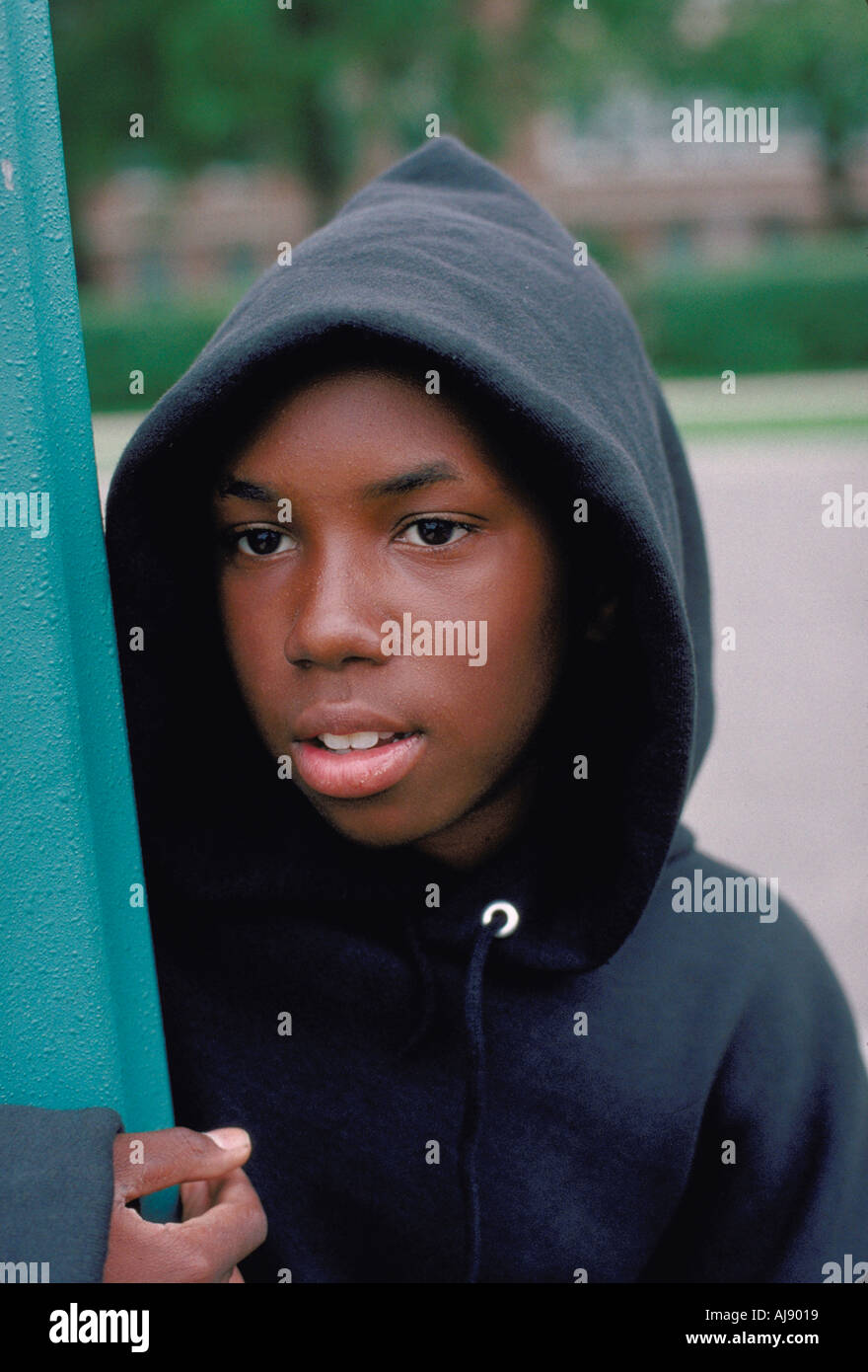 African American teen age 13 standing by a street sign wearing a hooded sweat shirt. St Paul Minnesota USA Stock Photo