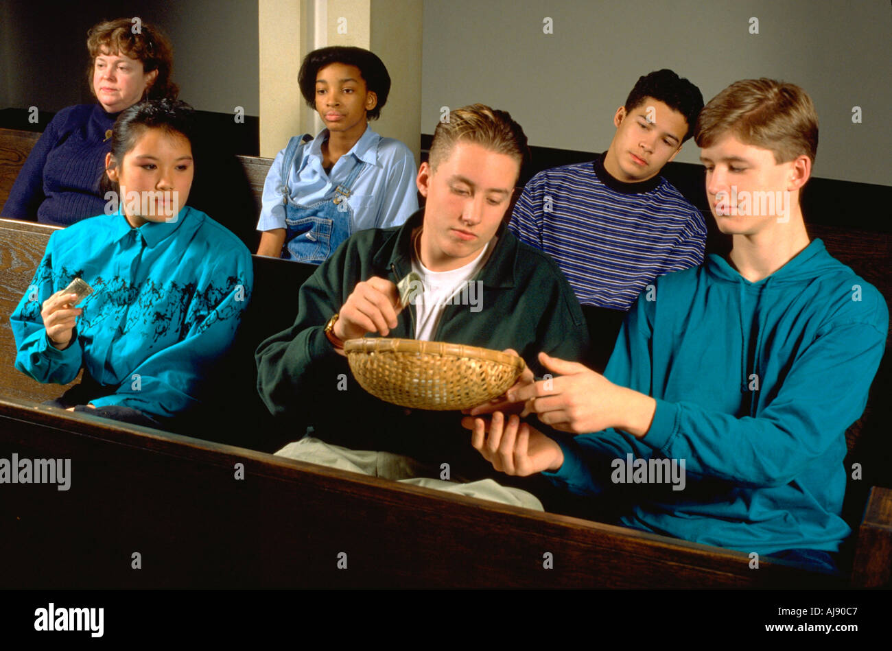 Racially mixed group of teens passing offering basket in church. St Paul Minnesota USA Stock Photo