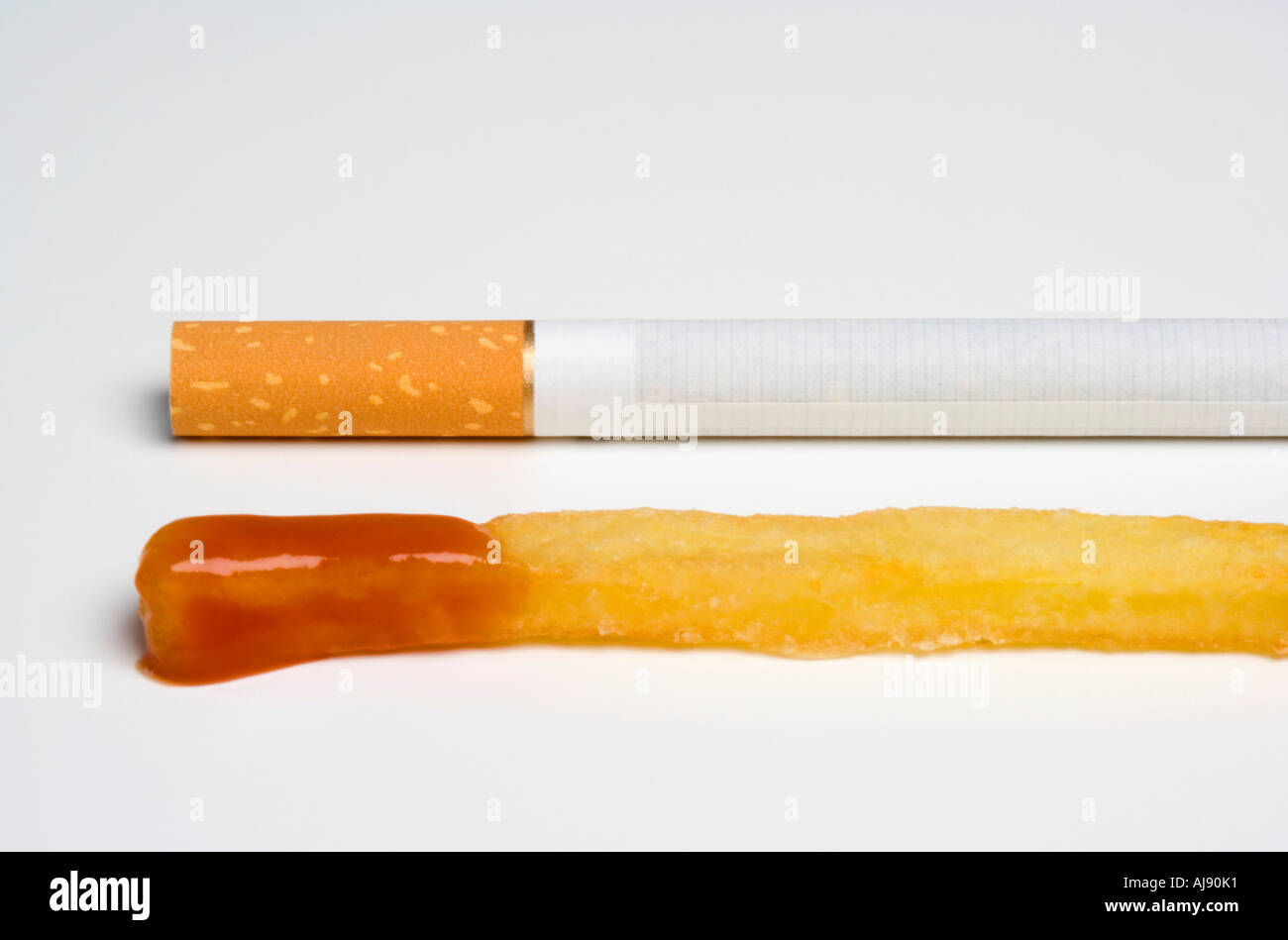 Cigarette next to french fry with ketchup Stock Photo