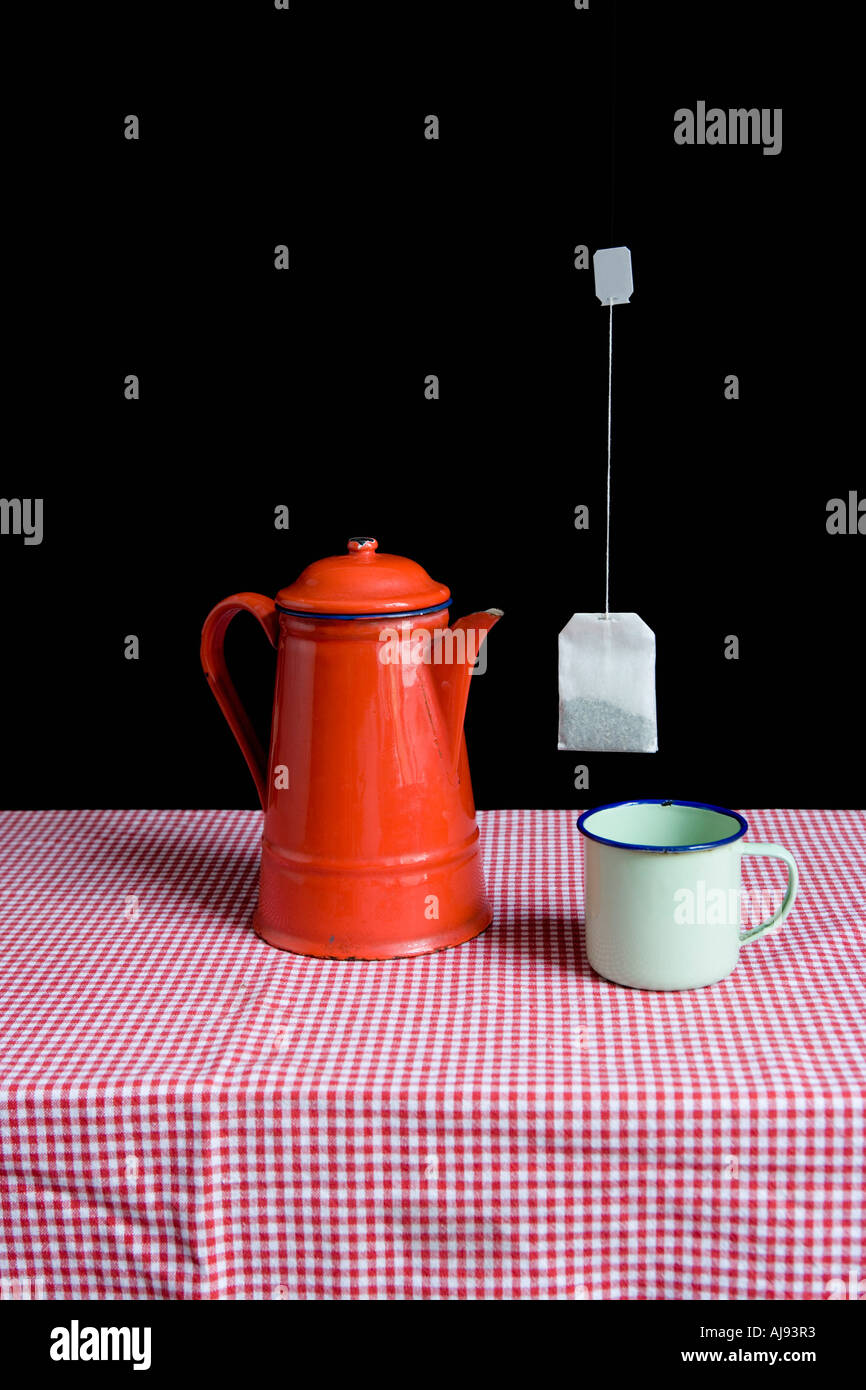 Enamel teapot and cup on table with teabag floating mid air Stock Photo Alamy