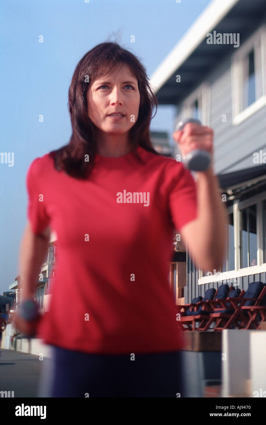 A woman fitness walking with hand weights along a beach strand path Stock Photo