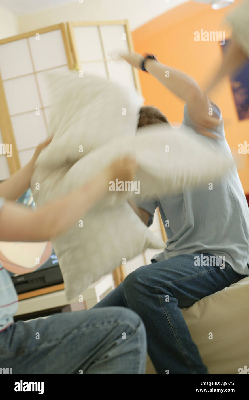 Teenage boys having pillow fight in lounge room Stock Photo