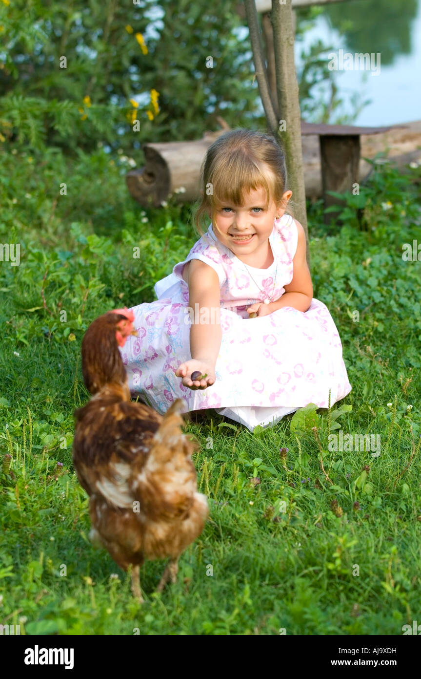 Portrait of cute 4 year old girl outdoor playing with chicken hen Stock Photo