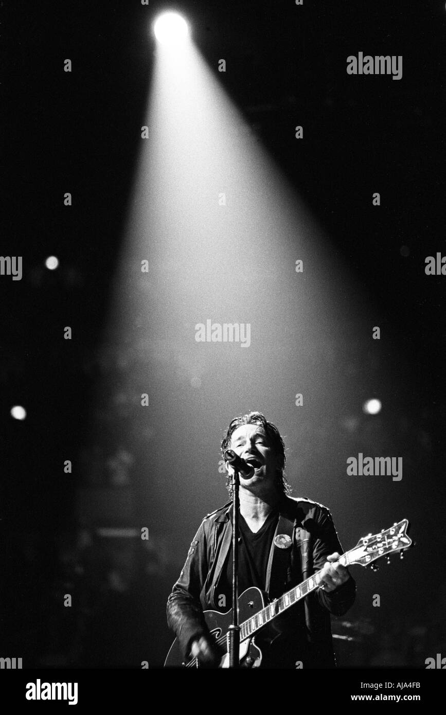 Bono in the spotlight playing guitar and singing live on stage Stock Photo