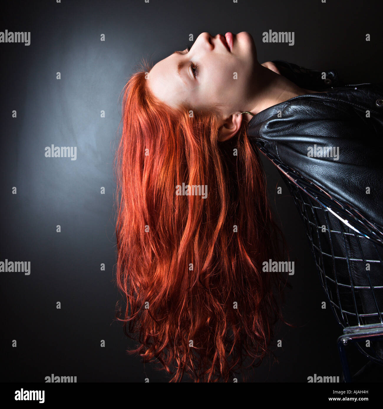 Pretty Redhead Young Woman Wearing Leather Jacket Leaning Back In Chair