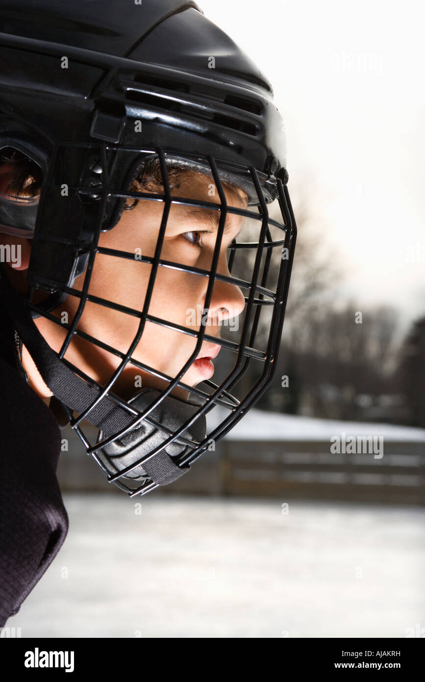 Ice hockey player boy in uniform and cage helmet concentrating Stock