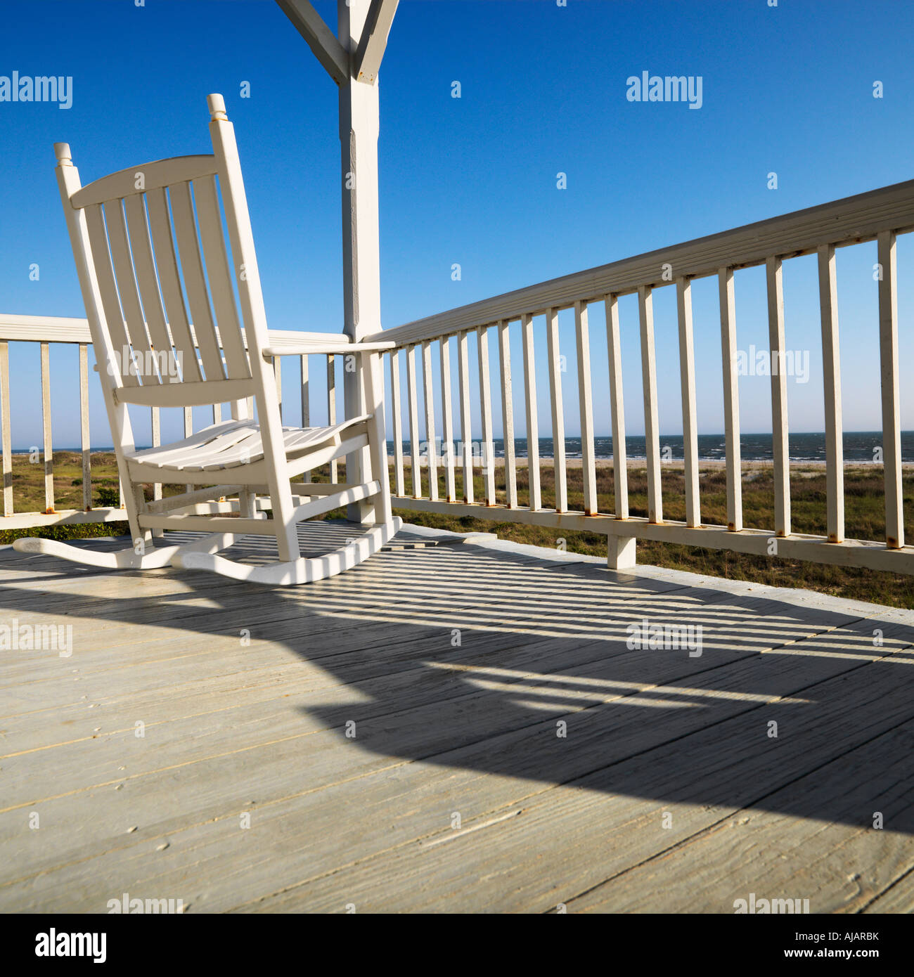 Rocking chair on porch with railing overlooking beach at Bald Head