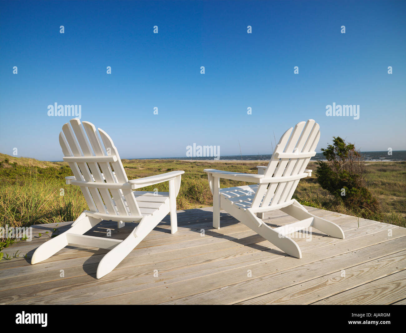 Two adirondack chairs on wooden deck overlooking beach at Bald Head