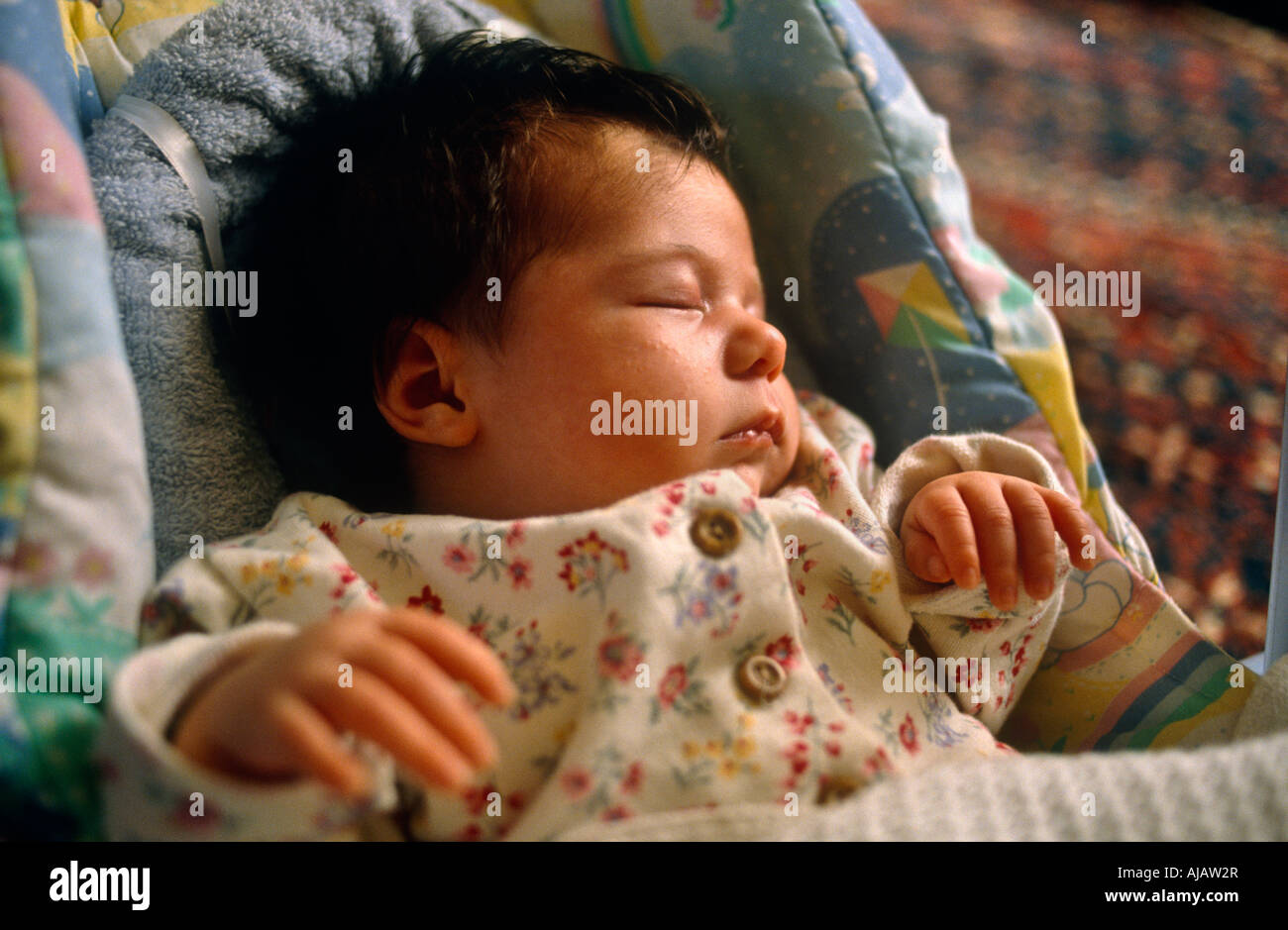 As window light falls over her face a baby girl sleeps soundly in her baby bouncer chair on the