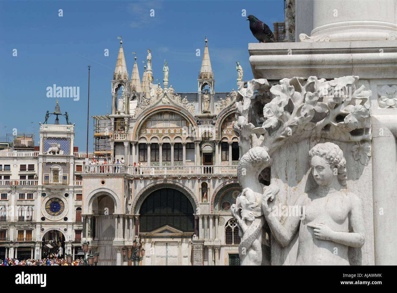 Detail of Sculpture of Eve and the serpent on Ducal Palace Doge residence at St Marks square with San Marco clock tower with Moors hitting bell Venice Stock Photo