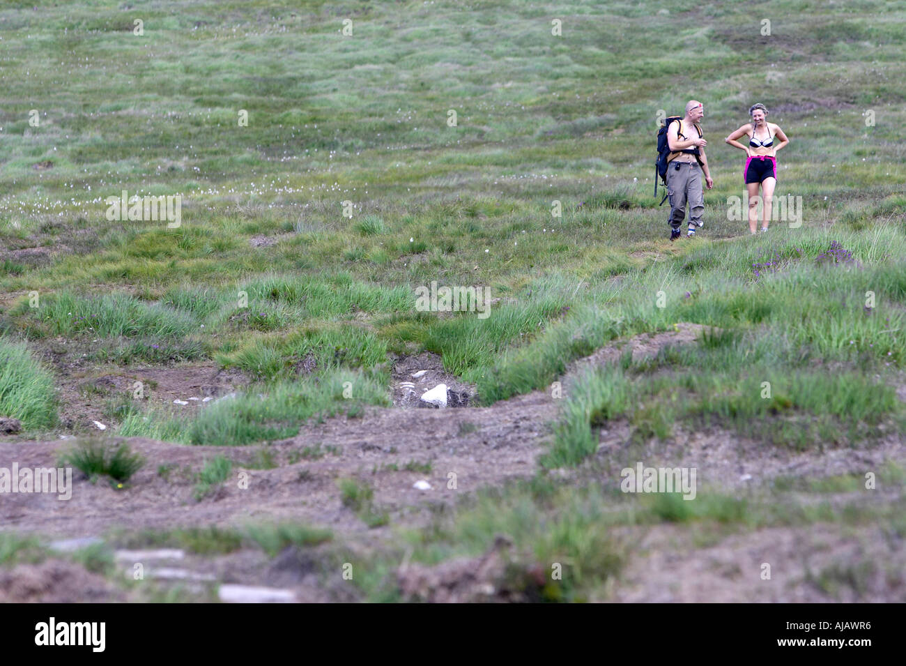 summer male and female climbers walking through peat bog at base of Errigal mountain donegals highest peak Stock Photo