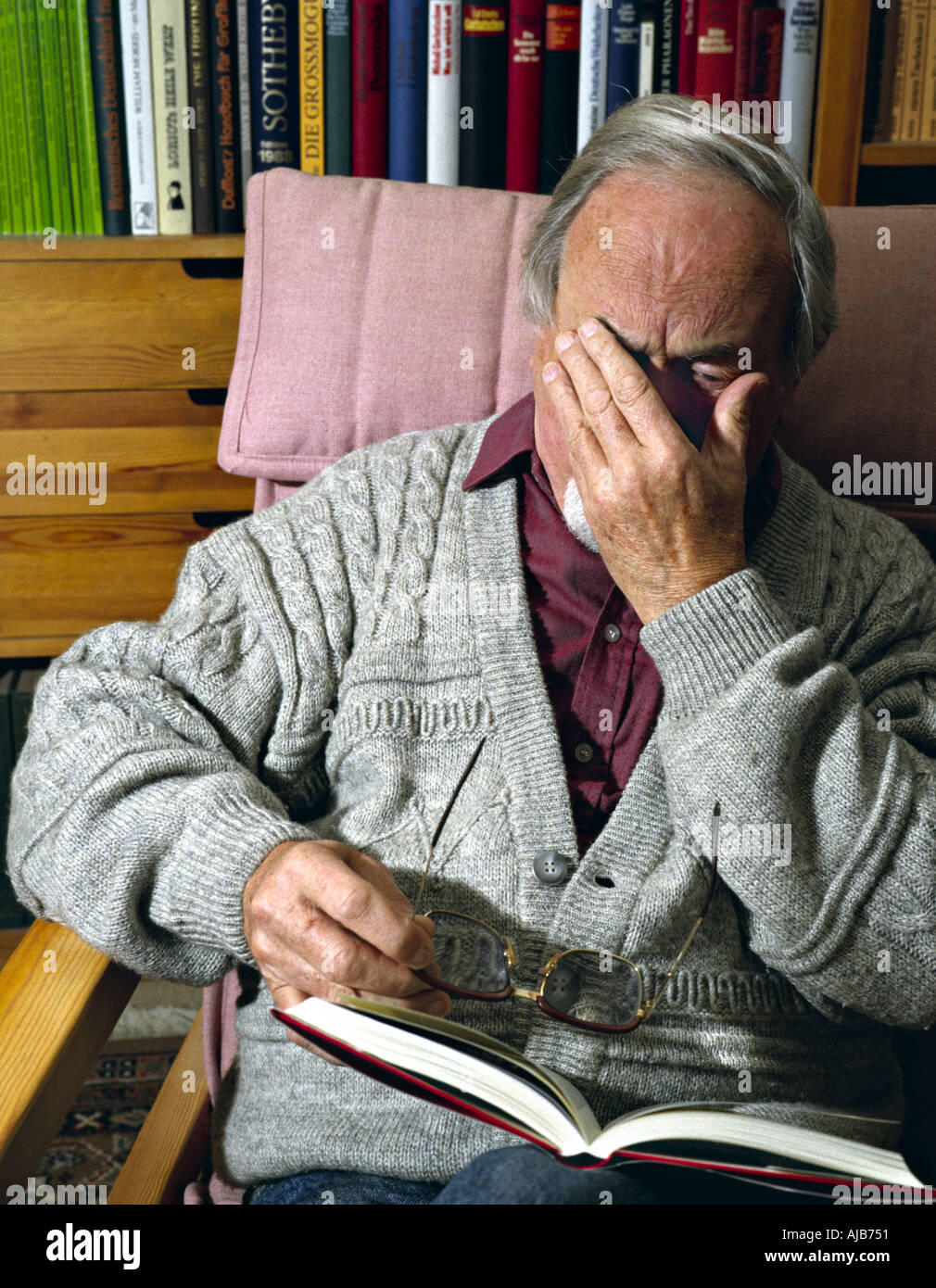 old man sitting in an armchair and reading a book Stock Photo - Alamy