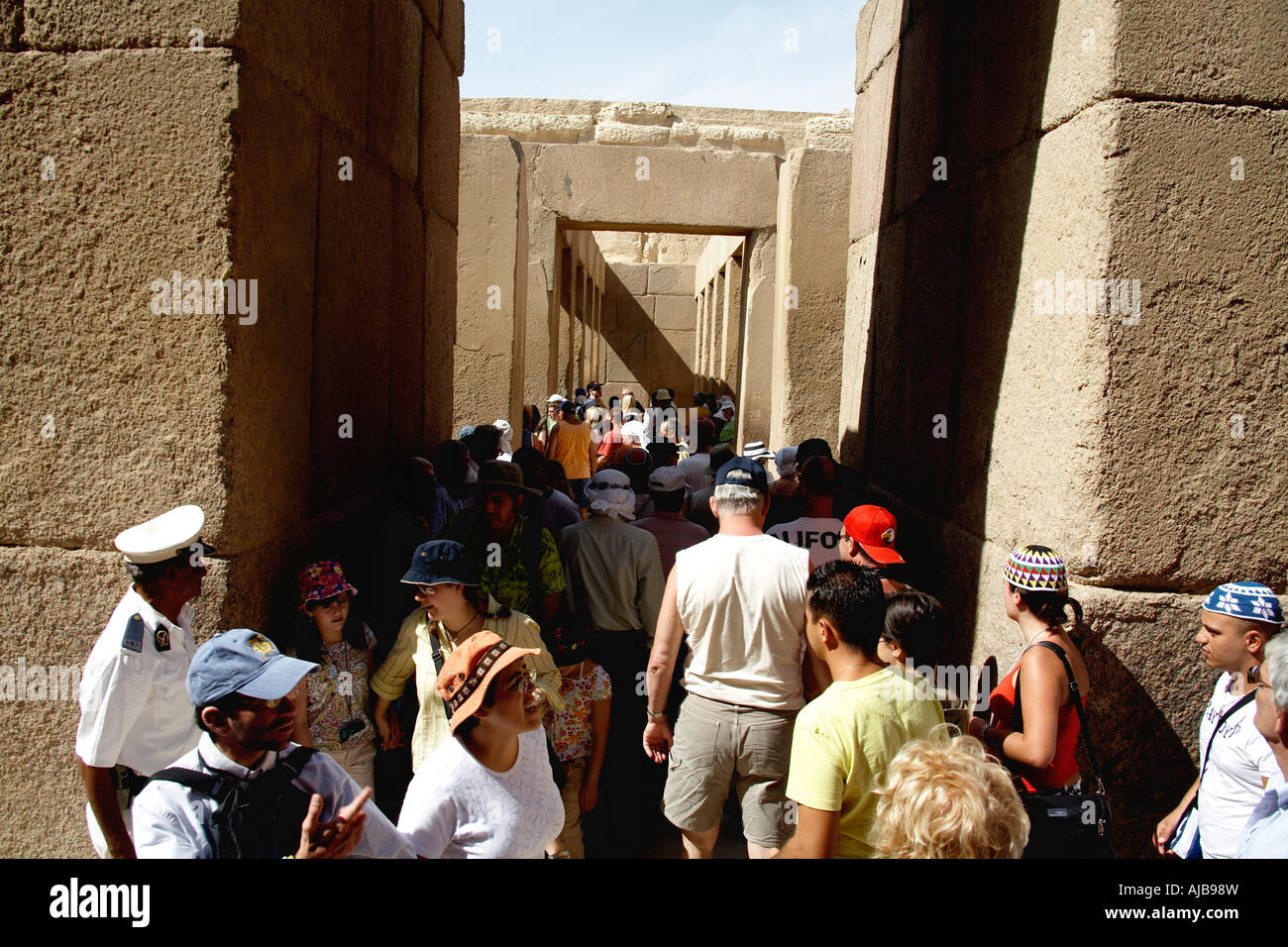 tourist visitors in tour groups walking around close fitting cut stone blocks of Khafre s Valley Temple Giza Cairo Egypt Africa Stock Photo