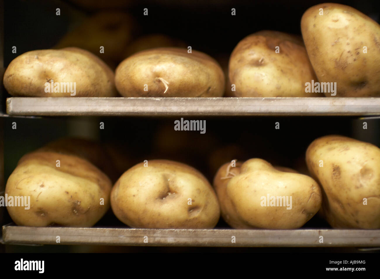 Raw uncooked potatoes on trays for baking baked jacket potato Stock