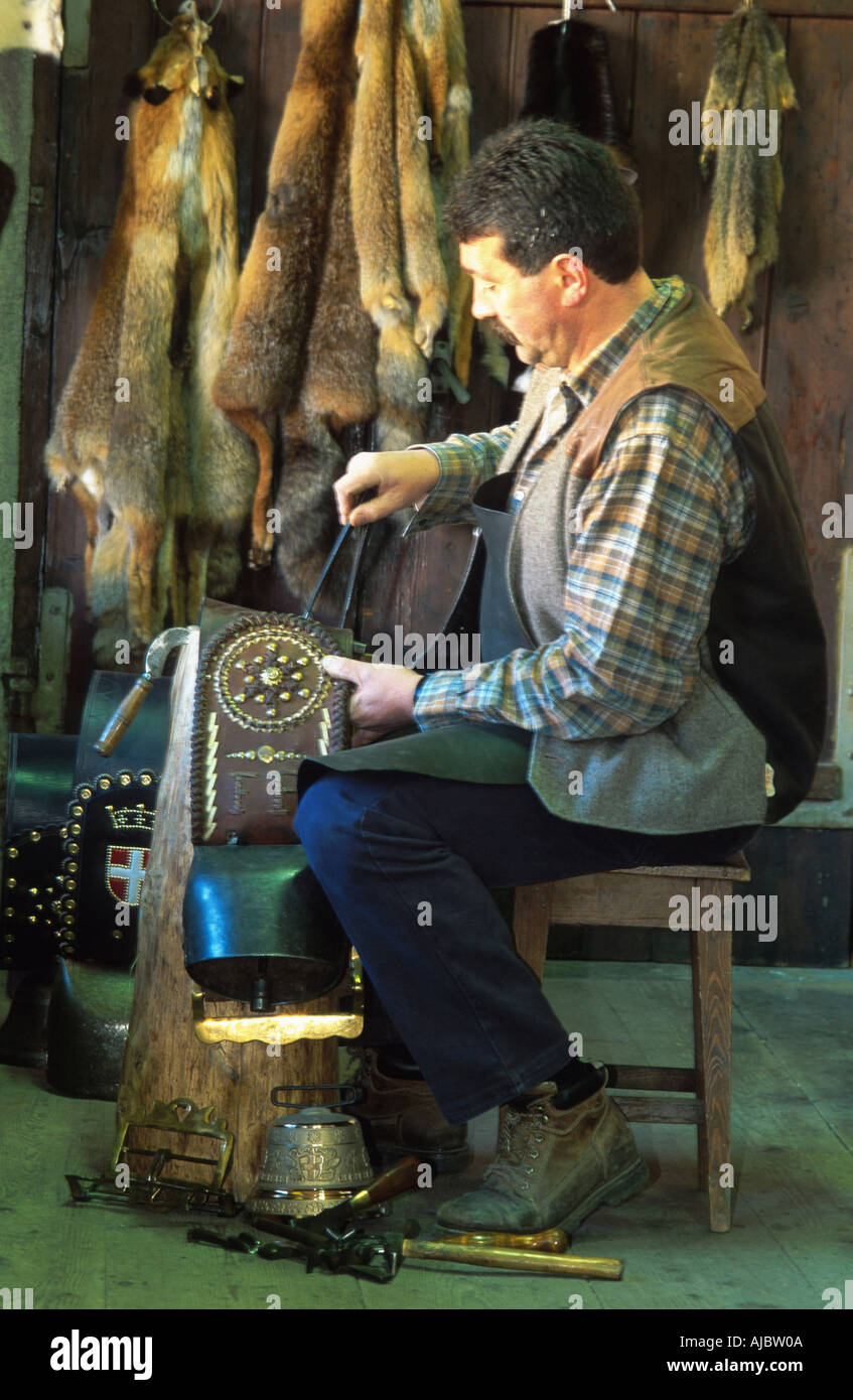 saddler making cow bells, sitting on chair Stock Photo