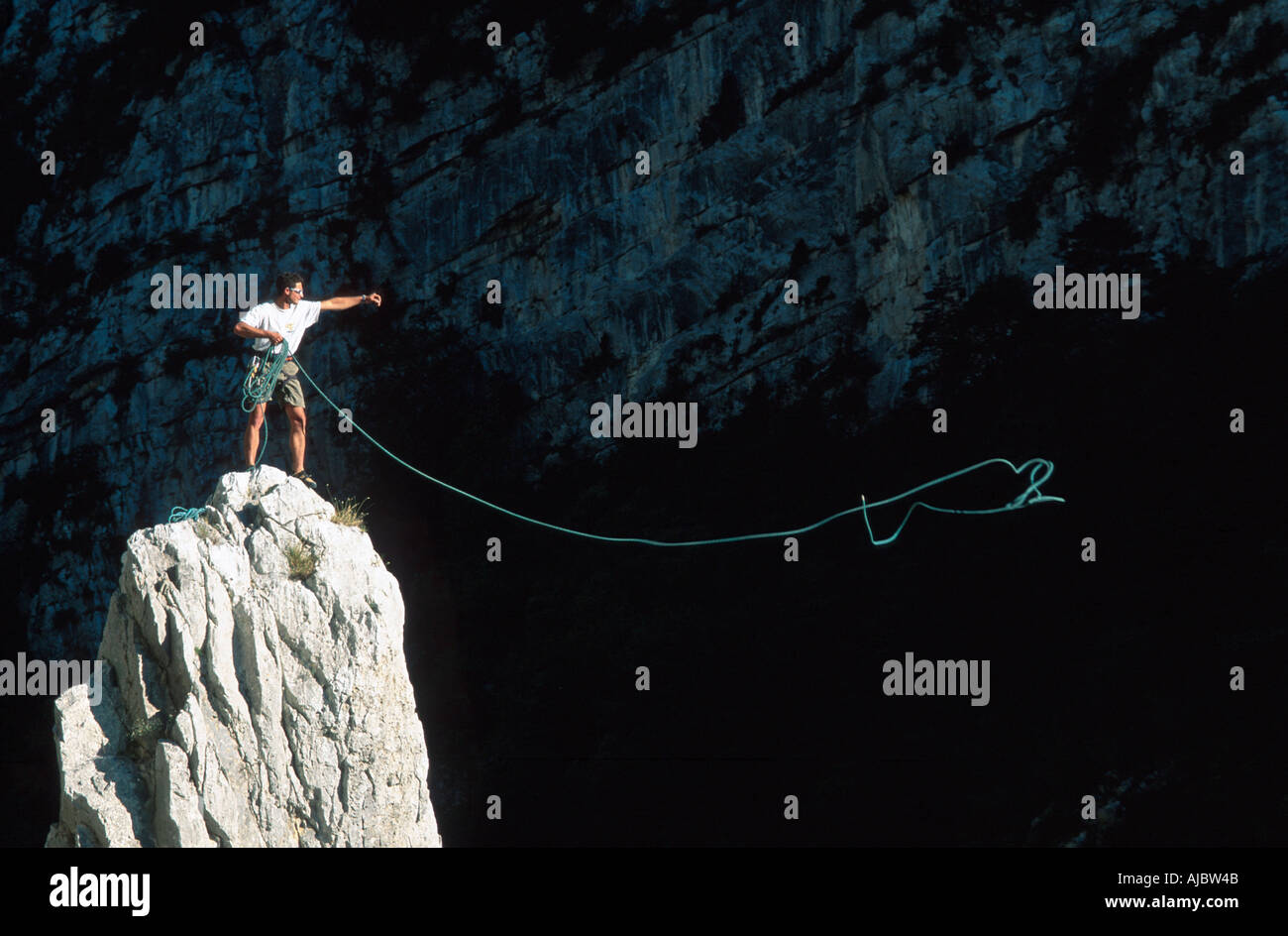 climber on rock needle, throwing climbing rope, France, Provence