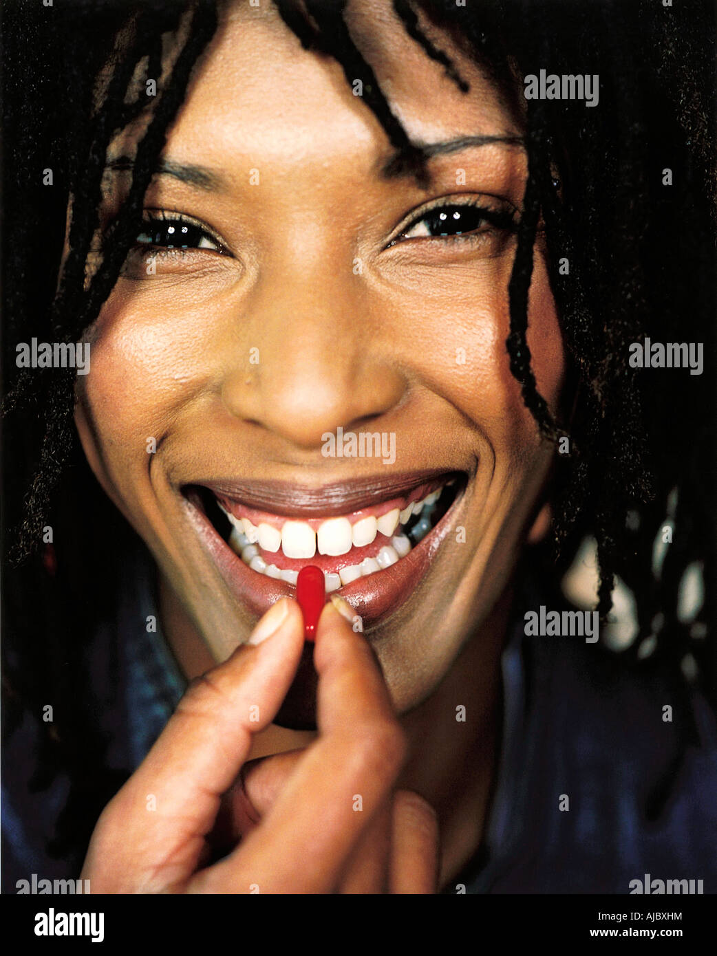 African Woman Holding a Pill (Capsule) Between Her Teeth Stock Photo