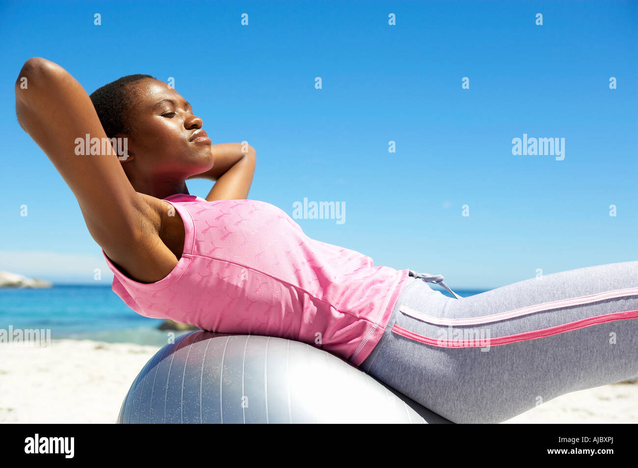 African Woman Exercising on the Beach - Side View Stock Photo