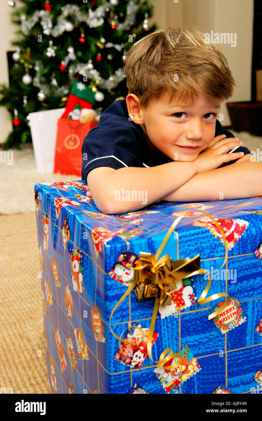 Portrait of a Young Boy Leaning on a Large Christmas Gift Stock Photo