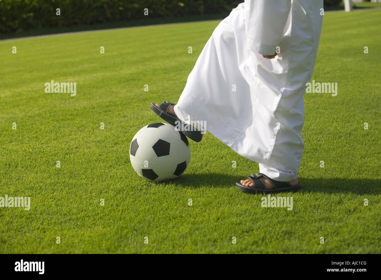 Young Arab Boy Playing Football on the Grass in the Park Stock Photo