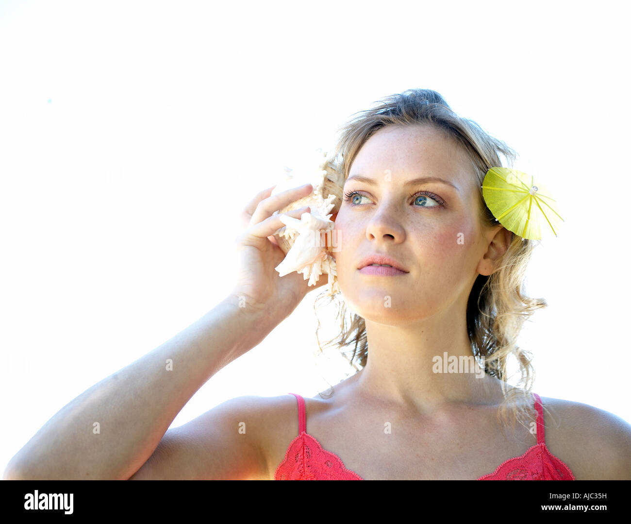 Young Woman Holding a Shell to her Ear Stock Photo - Alamy