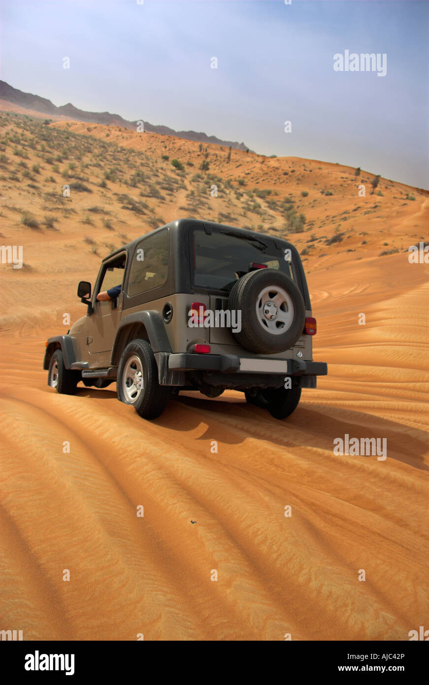 Green 4x4 Driving over Dunes in the Desert Stock Photo