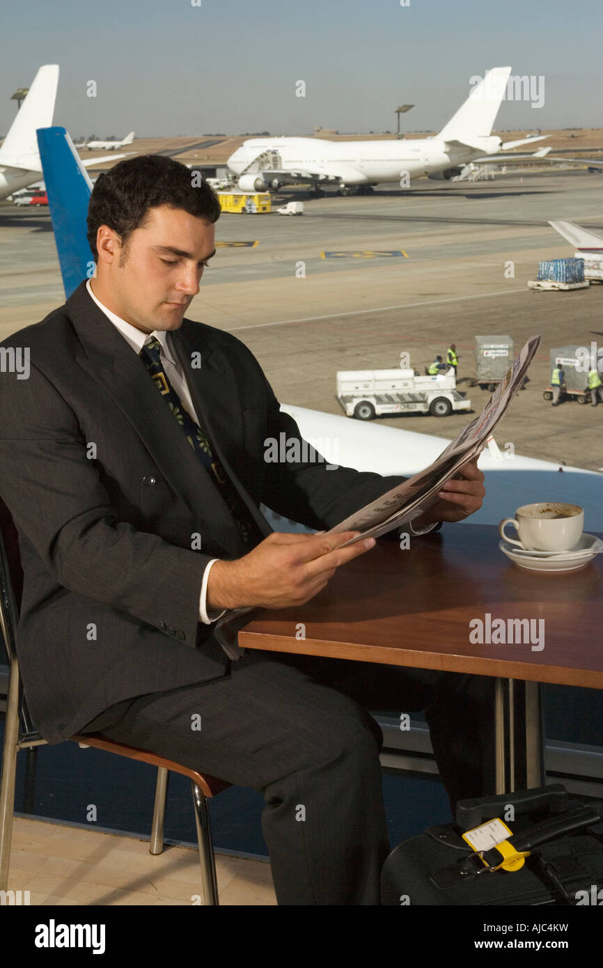 Businessman at an Airport Restaurant Reading a Newspaper Stock Photo