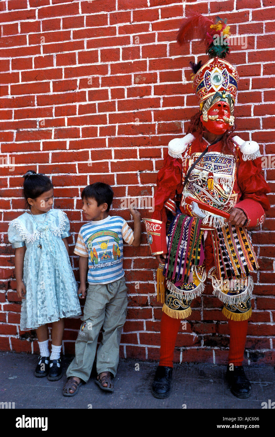 Two children stand beside a masked dancer Cuyotenango Guatemala Stock Photo