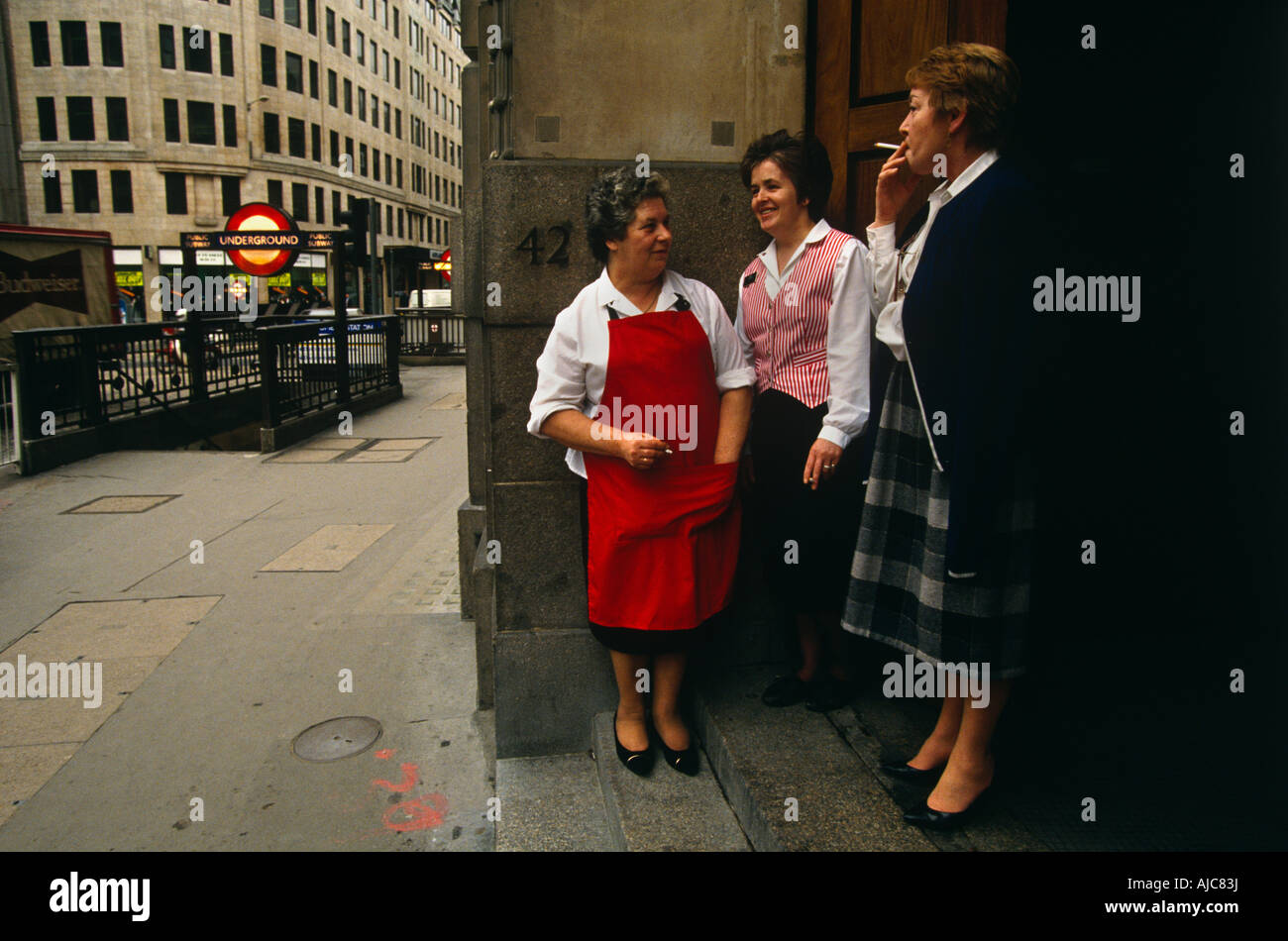 Middle-aged women office workers take a cigarette break outside their place of work in the City of London. Stock Photo