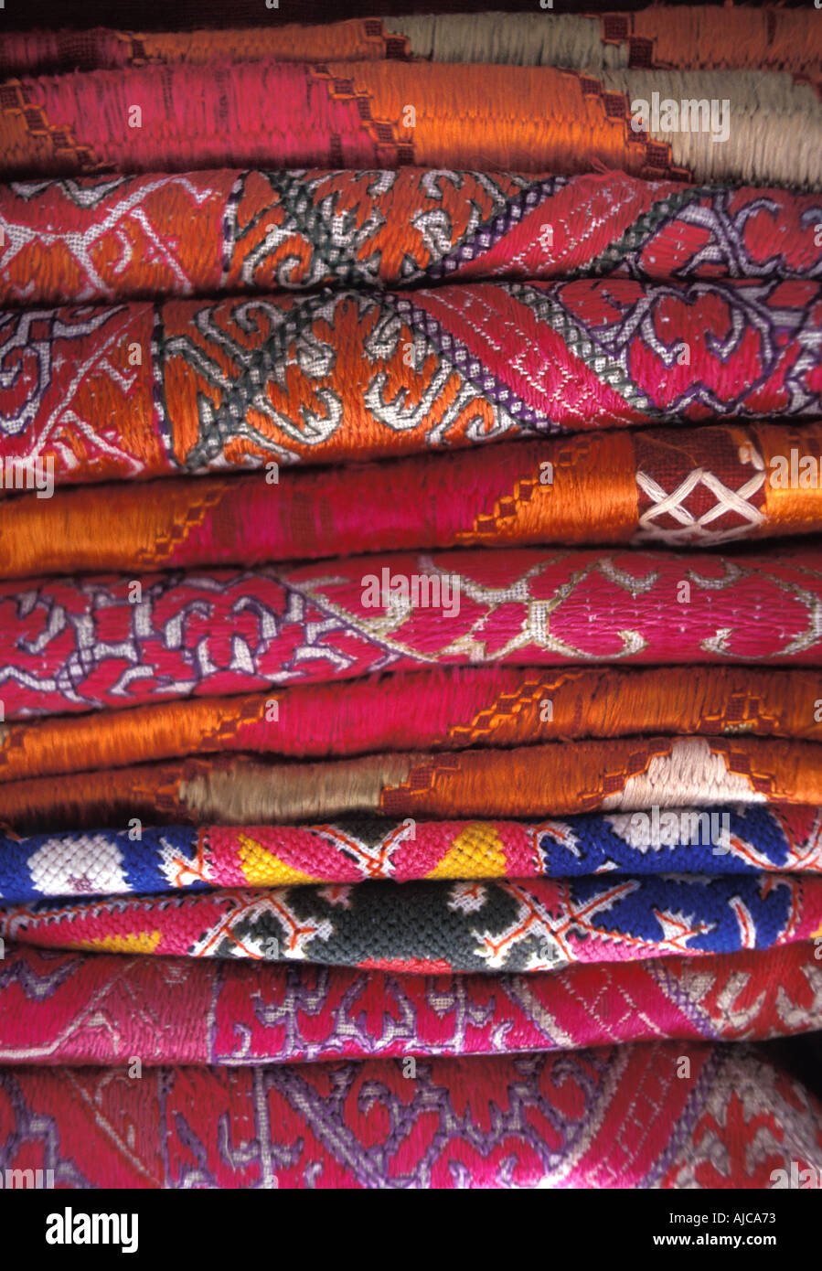 Stack of everyday and ceremonial hand embroidered silk and woven