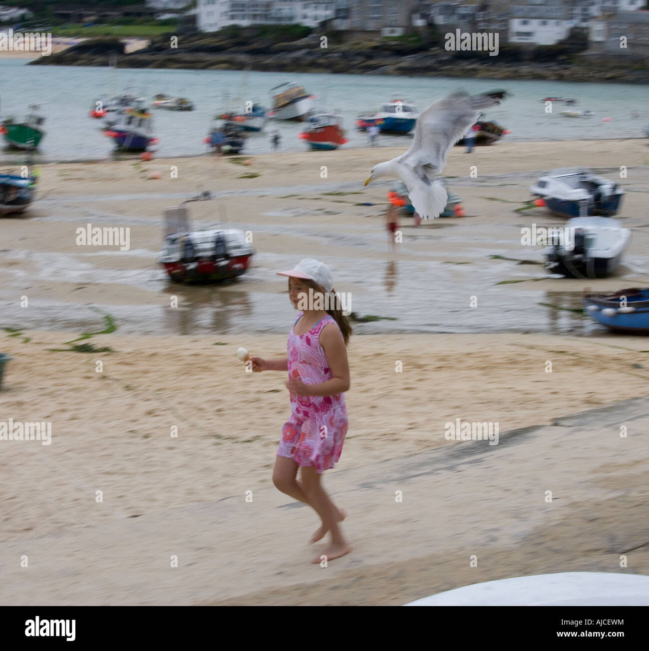 young girl with ice cream running to avoid attack by a herring gull