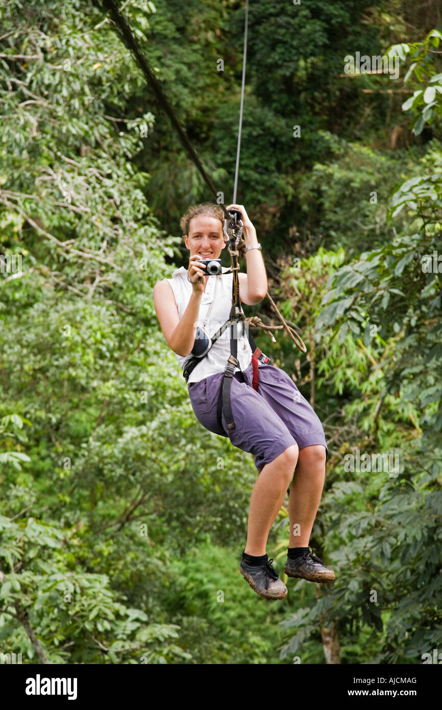 Woman taking a photograph while on a zip line at The Gibbon Experience, near Huay Xai, on the Mekong river near in Laos Stock Photo