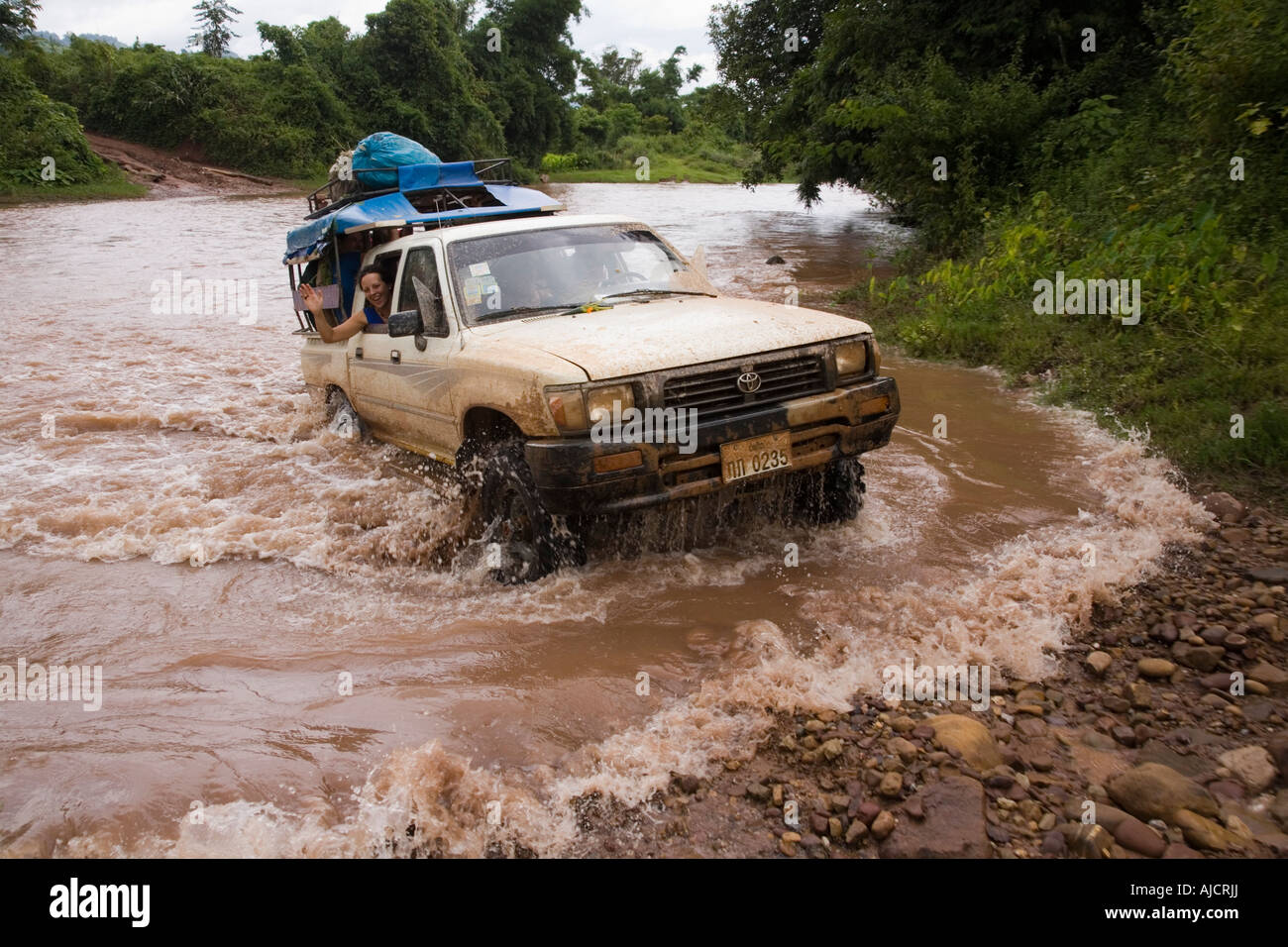 Four wheel drive vehicle crosses river at The Gibbon Experience near Huay Xai on the Mekong river near the Laos Thai border Stock Photo