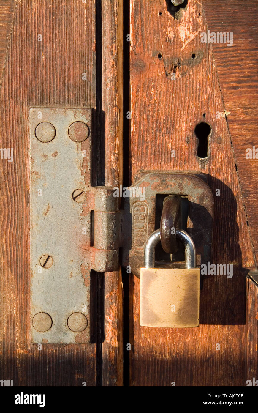Old wooden double door fastened by padlock and hasp Stock Photo