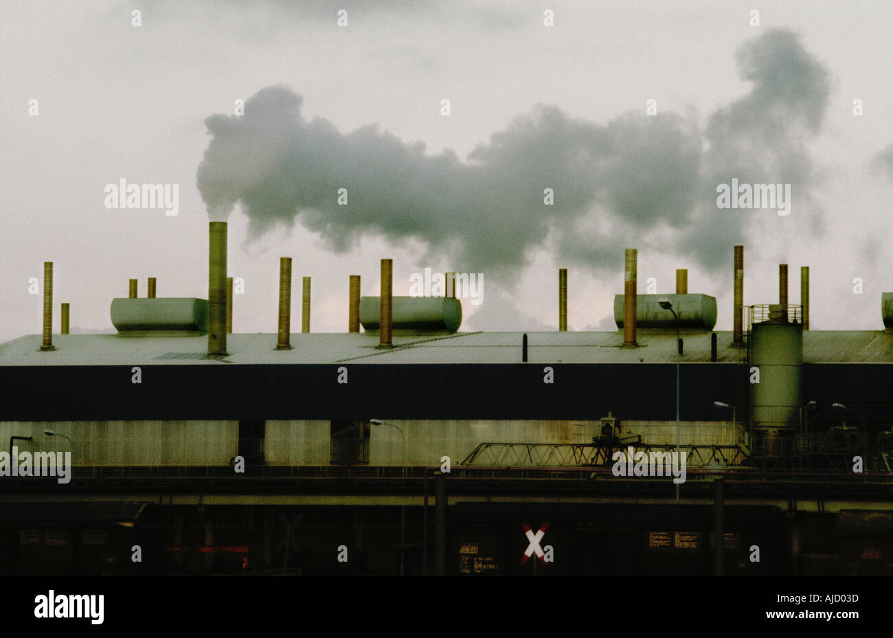 Gloomy setting with old factory emitting polluting smoke from a chimney. Stock Photo