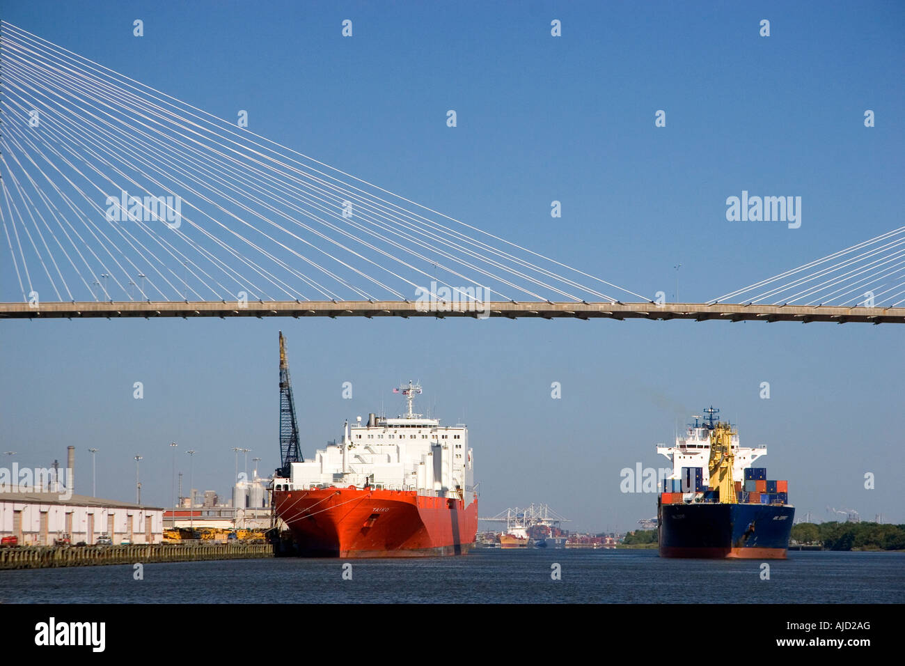 Container ships pass under the Talmadge Memorial Bridge on the Savannah River at the Port of Savannah in Savannah Georgia Stock Photo