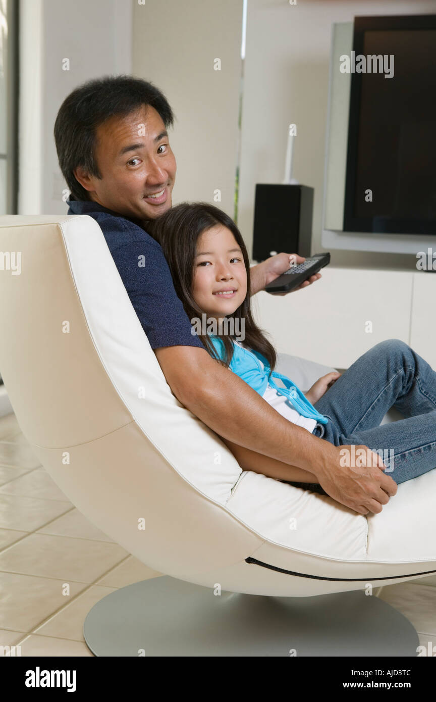 Father and Daughter preparing to watch television in living room, portrait Stock Photo