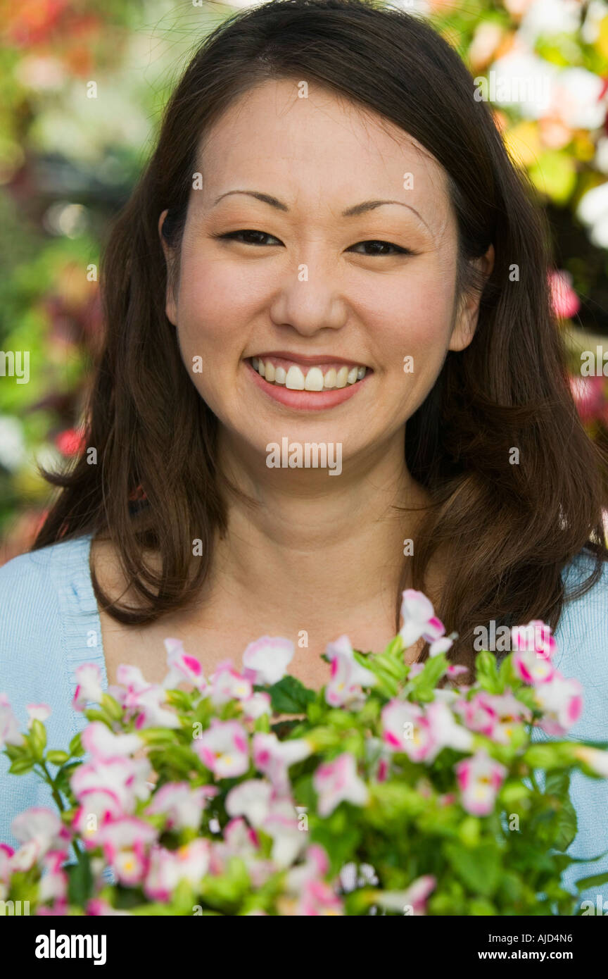 Woman Holding Flowers in plant nursery, portrait, close up Stock Photo