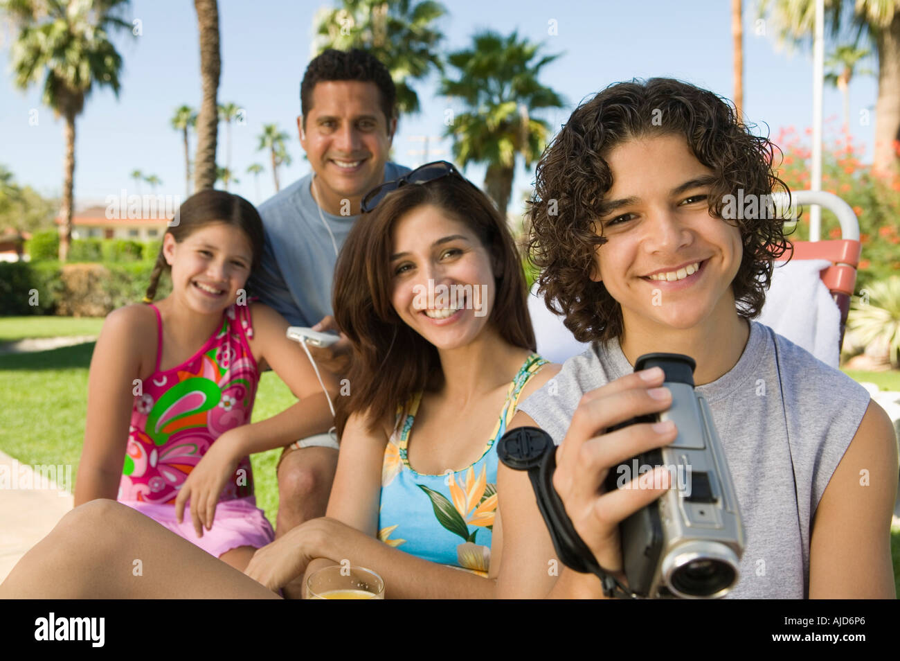 Boy (1315) holding camcorder, sitting outdoors with sister (79) and