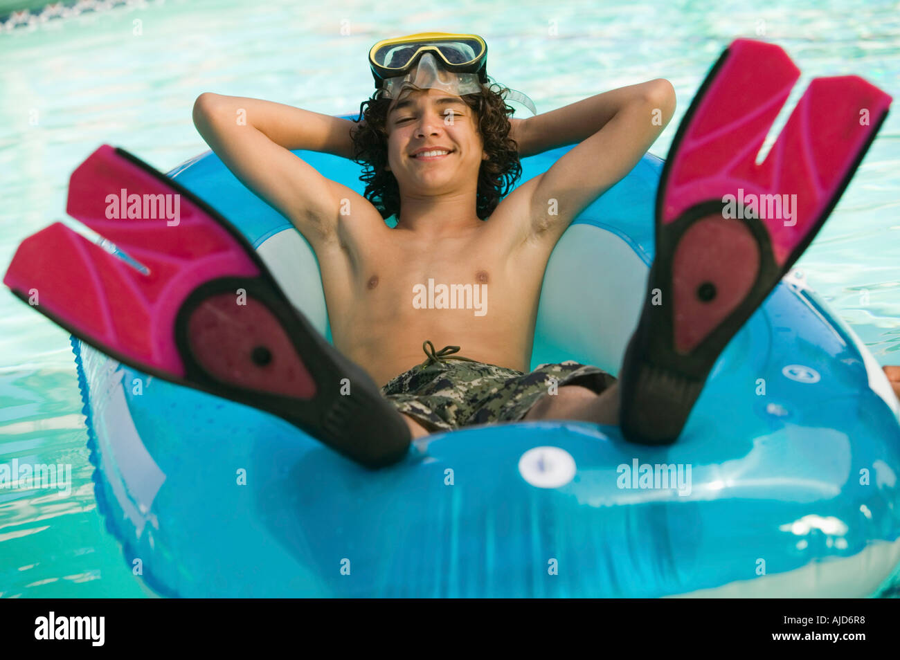 Boy (1315) wearing flippers and swim goggles, lying on inflatable raft