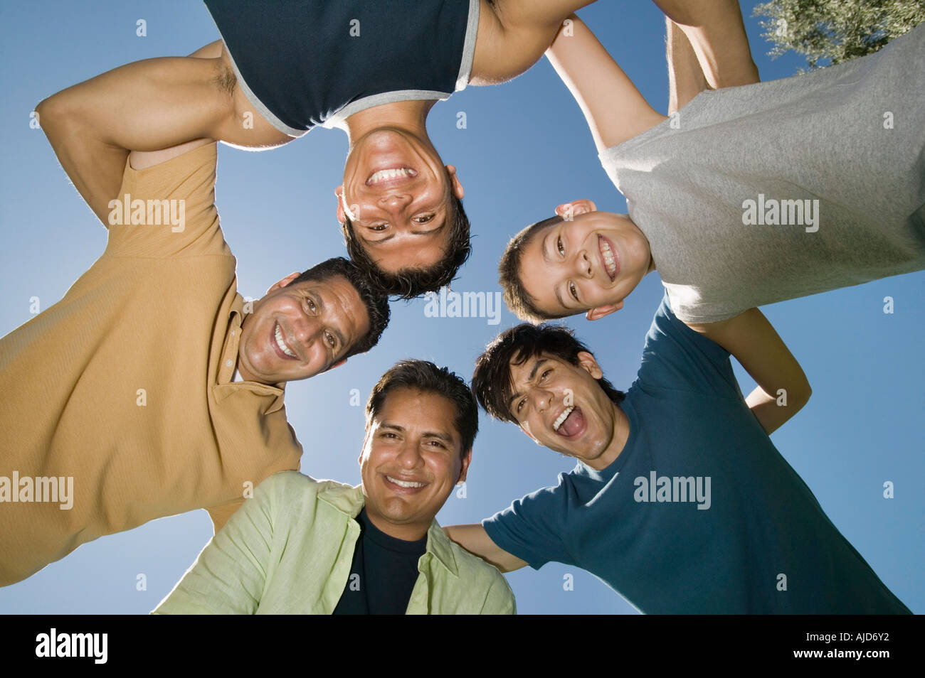 Boy (13-15) with brothers and father in a huddle, view from below. Stock Photo