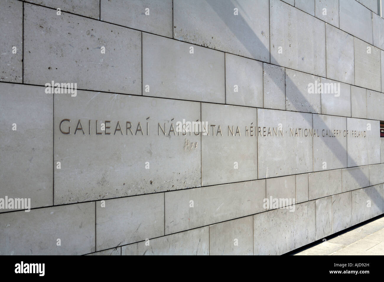 Wall outside the National Gallery of Ireland with 'National Gallery of Ireland' written chiseled on it in the Irish Language Stock Photo