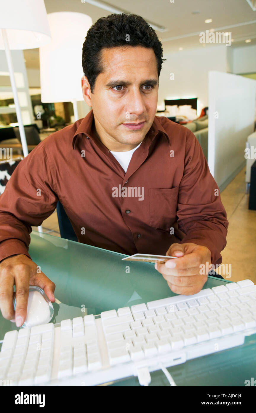 Concerned man running credit card through computer in furniture store