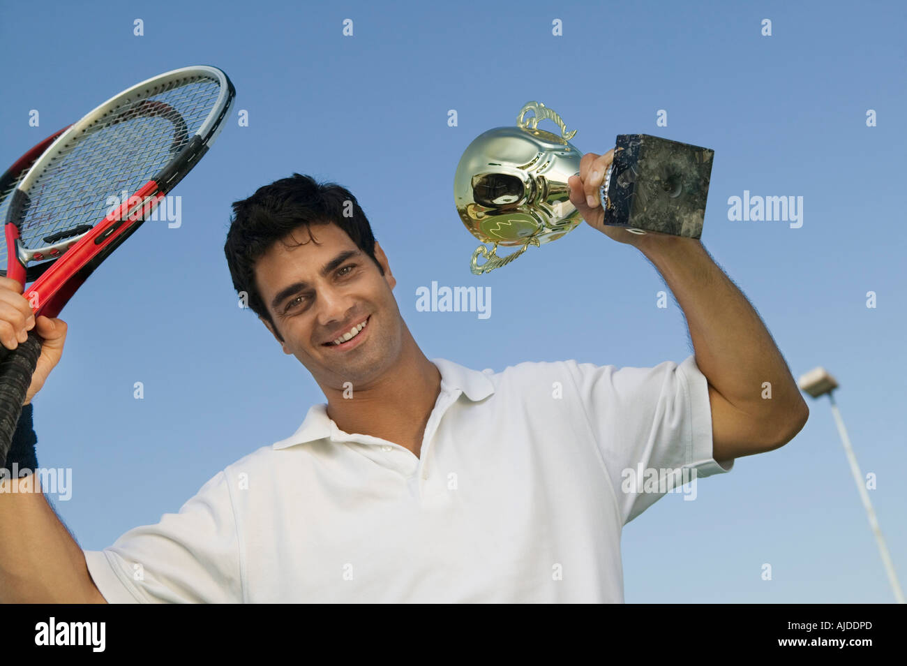 Male Tennis Player raising tennis rackets and Trophy, portrait Stock ...