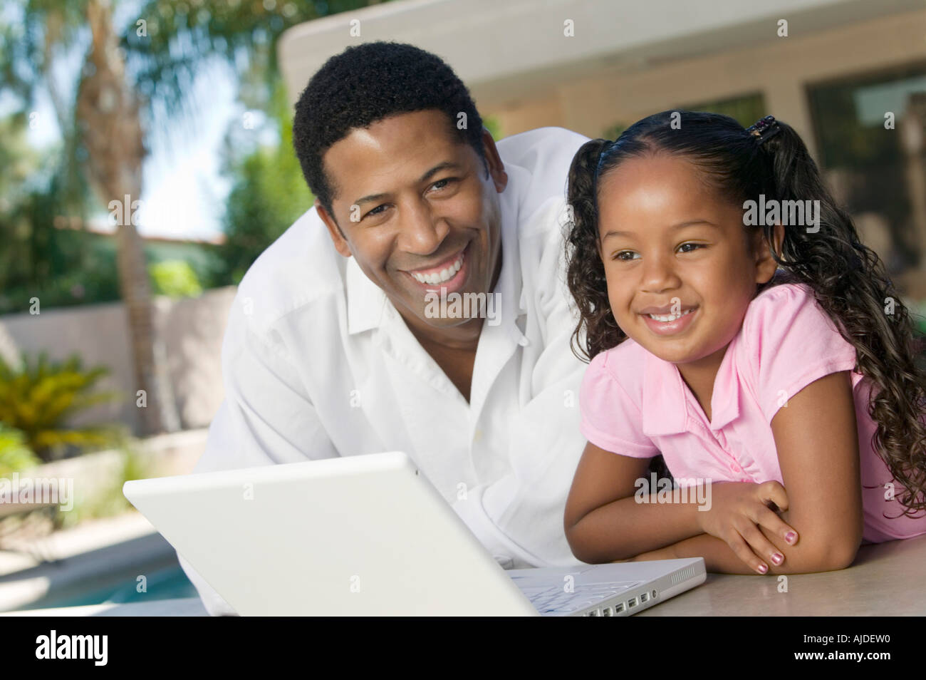 Father and Daughter Using Laptop on patio, portrait Stock Photo
