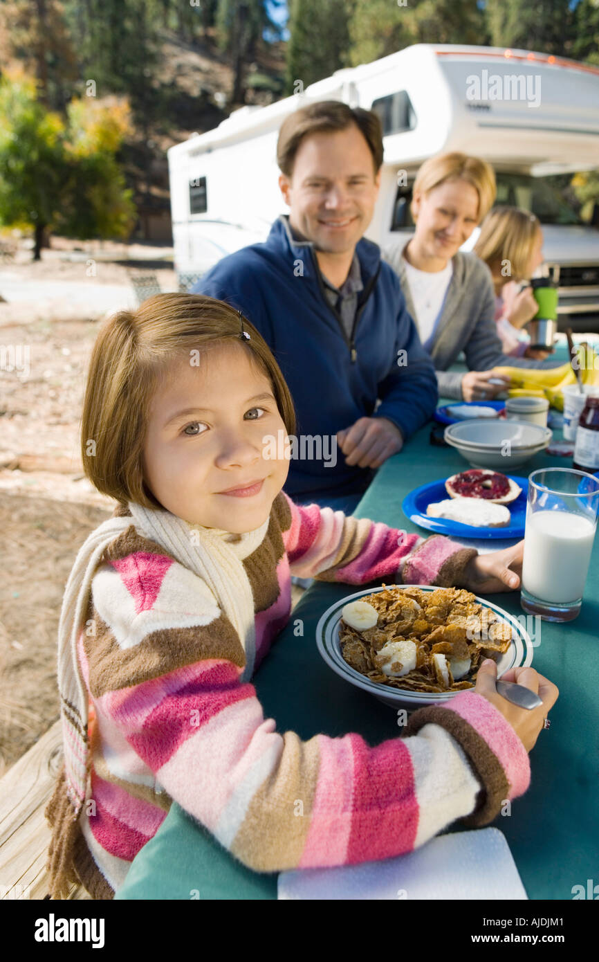 Girl eating at picnic table with family in campground Stock Photo Alamy