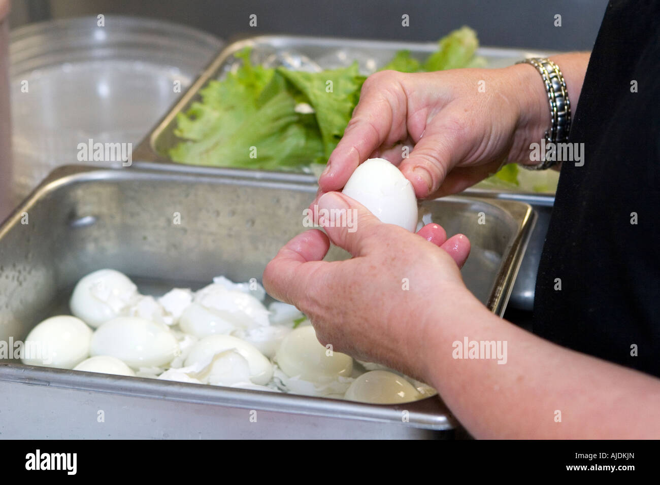Kitchen staff remove shells off of hard boiled eggs to be used in fresh