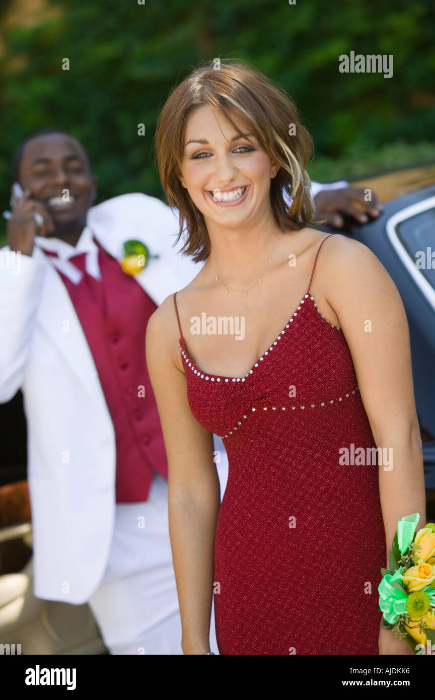 Teenage girl in dress outside limo with date behind, portrait Stock Photo