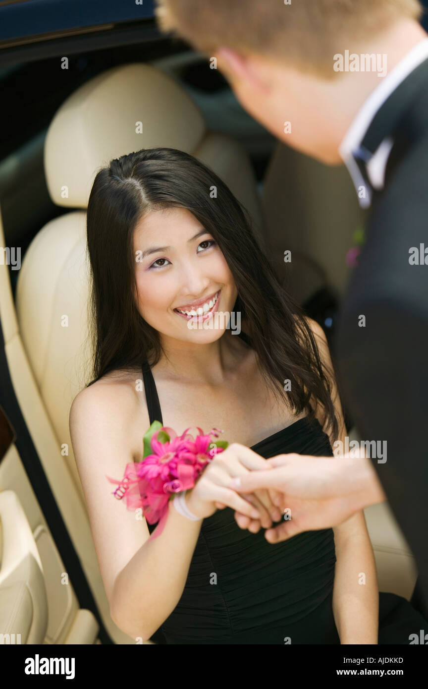 Well-dressed teenager girl being helped out of limo by date Stock Photo